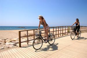 two women riding bikes on a boardwalk near the beach at MAEVA HomeStay by Turismar in Cambrils