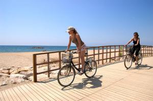 カンブリルスにあるMAEVA HomeStay by Turismarのビーチ近くの遊歩道で自転車に乗る女性2名