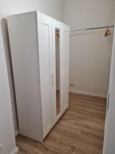 Cette chambre comprend une armoire blanche et un miroir. dans l'établissement Ferienwohnung Ida an der Flensburger Förde, à Flensbourg