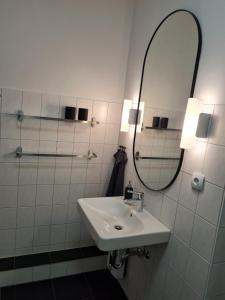 La salle de bains blanche est pourvue d'un lavabo et d'un miroir. dans l'établissement Ferienwohnung Ida an der Flensburger Förde, à Flensbourg