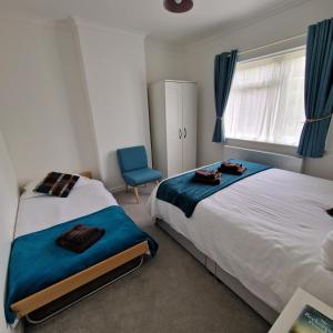 a bedroom with two beds and a blue chair at Stylish bungalow with complimentary breakfast on the first morning in Lancing