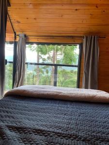 ein Schlafzimmer mit einem Bett und einem großen Fenster in der Unterkunft Cabana Canela in Urubici