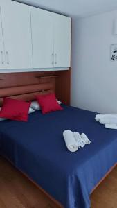 a blue bed with two white towels and red pillows at La Dimora di Maggie in Florence