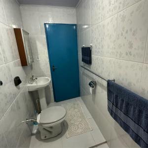 a bathroom with a toilet and a blue door at Recanto São Francisco in Campos do Jordão