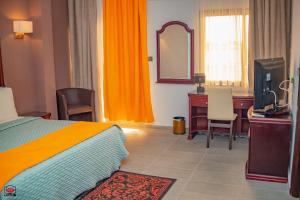 a bedroom with a bed and a desk and a television at Mayombe Arena Hotel in Pointe-Noire