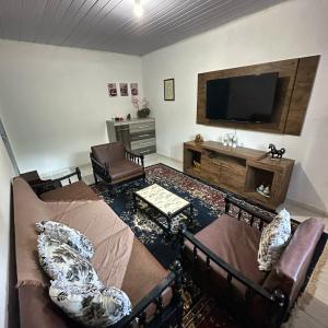 a living room with couches and a flat screen tv at Recanto São Francisco in Campos do Jordão