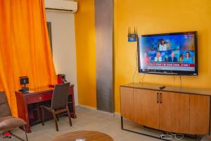 a living room with a tv on a yellow wall at Mayombe Arena Hotel in Pointe-Noire