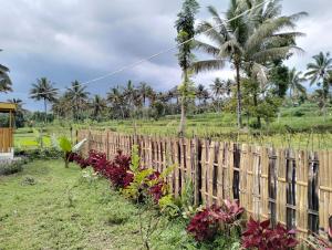 a wooden fence in a garden with flowers at Sunset Point Kembang Kuning in Tetebatu
