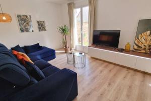 uma sala de estar com um sofá azul e uma televisão de ecrã plano em Les Glazons *T4* Olivet + Parking em Olivet