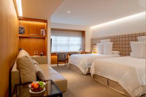 a hotel room with two beds and a couch at Hotel Emiliano in São Paulo