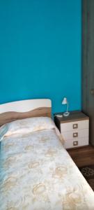 a bedroom with a blue wall and a bed and a nightstand at Villa - Malibu' in Lauria Inferiore