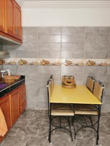 een gele tafel en stoelen in een keuken bij Chez Marie in Al Ghar