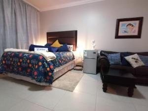 a bedroom with a bed and a couch at Mi Vida Guesthouse in Klerksdorp