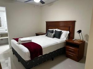 a bedroom with a large bed and a night stand at Merliot, Sta Tecla Frente Cto Comer La Plaza Merliot in Nueva San Salvador