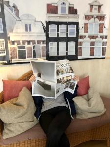 una persona tirada en un sofá leyendo un periódico en B&B Hotel Goldener Hahn - Guesthouse Hirsch Baiersbronn, en Baiersbronn