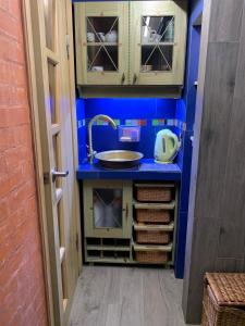 eine kleine Küche mit einem Waschbecken und blauen Wänden in der Unterkunft Студія з внутрішнім півповерхом. in Mykolajiw
