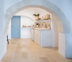 a kitchen with an arched doorway and white cabinets at Rosa Trulli suite in Alberobello
