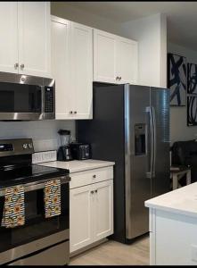 a kitchen with a stainless steel refrigerator and white cabinets at Luxurious 3 Story Townhome in Charlotte