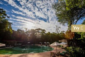 uma vista para uma piscina com árvores e nuvens no céu em Yvy Hotel de Selva em Porto Iguaçu