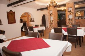 un restaurante con mesas y sillas blancas y mantel rojo en Hanul Cappsha en Oradea