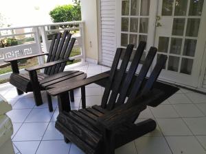 a pair of wooden chairs sitting on a porch at Mystic Ridge Apt 2 Plus 6 in Ocho Rios