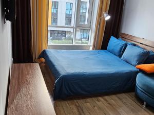 sypialnia z niebieskim łóżkiem i oknem w obiekcie Abay 130 w mieście Ałma-Ata