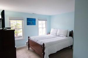 a bedroom with a bed with blue walls and two windows at Cozy 2br home w/ parking in downtown Annapolis in Annapolis