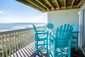 three chairs and a table on a porch with the ocean at Oceanfront Condo with 3+ Pools - Ocean Dunes 502 in Kure Beach