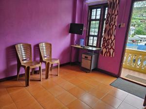 2 sillas en una habitación con una pared púrpura en Cicily Holidays Inn en Munnar