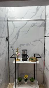 une étagère en verre avec une cafetière sur une table avec des plantes dans l'établissement غرفة وصالة في أبها, à Abha