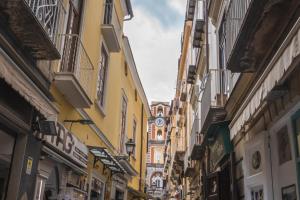 a narrow street with buildings and a clock tower at Room Giuliani in Sorrento