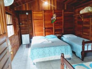 1 Schlafzimmer mit 2 Betten und Holzwänden in der Unterkunft Pousada do Cowboy in Sapucaí-Mirim