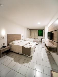 una camera d'albergo con due letti e una televisione di Hotel Praia Mar a Fortaleza