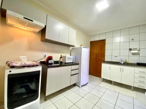 Una cocina con gabinetes blancos y un refrigerador blanco. en Apto espaçoso no Centro, térreo com 2 Quartos de Casal ArCond WiFi 400megas HomeOfice Cozinha e Garagem, en Dourados