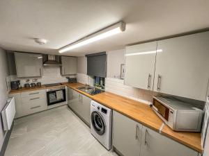 a kitchen with white cabinets and a washer and dryer at Grant House in Boston