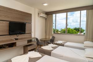 a hotel room with three beds and a flat screen tv at Hotel Praia Mar in Fortaleza