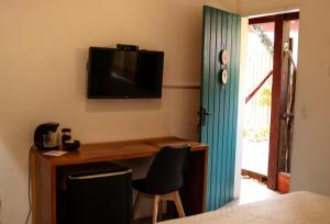a room with a desk and a television on the wall at Suites da Loja Caraíva in Porto Seguro