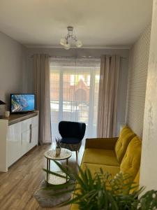 a living room with a yellow couch and a table at Apartament Alexa na Tatarskiej A in Przemyśl