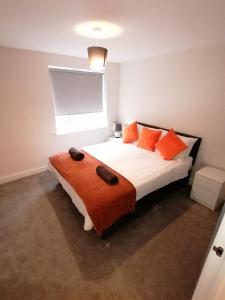 a bedroom with a bed with orange pillows and a window at Apollo Avenue Apartment in Stony Stratford