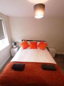 a bedroom with a large bed with orange pillows at Apollo Avenue Apartment in Stony Stratford