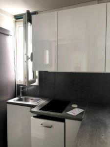 a kitchen with white cabinets and a sink at Studio calme à Bastille, proche Seine & Gare de Lyon in Paris