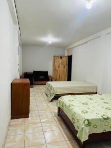 een hotelkamer met 2 bedden en een tegelvloer bij La casa de Elena in Tingo María