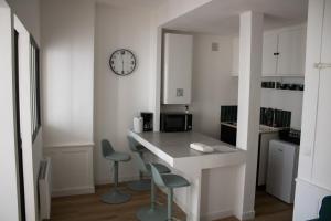 une cuisine avec un comptoir, deux chaises et une horloge dans l'établissement La Galerie de Lumière 201, à Aurillac