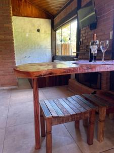 a wooden table with two wine glasses and a bench at Chalé Floresta Mauá in Resende
