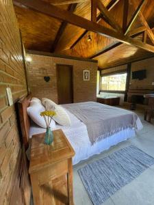 a bedroom with a bed and a table with a vase of flowers at Chalé Floresta Mauá in Resende