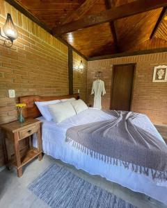 una camera con un grande letto e un muro di mattoni di Chalé Floresta Mauá a Resende