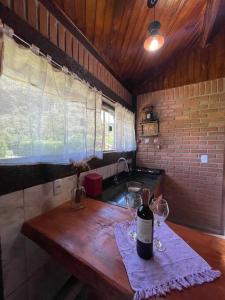 a bottle of wine sitting on a wooden table in a kitchen at Chalé Floresta Mauá in Resende
