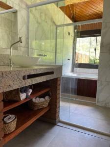 bagno con lavandino, vasca e specchio di Chalé Floresta Mauá a Resende