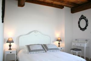 1 dormitorio con 1 cama blanca con 2 lámparas y espejo en Castel chambres, en Malves