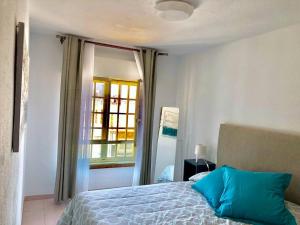 une chambre avec un lit avec des oreillers bleus et une fenêtre dans l'établissement Casa playa Las Canteras, à Las Palmas de Gran Canaria 17 autres photos